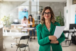 business woman in a green suit stands in an office workplace