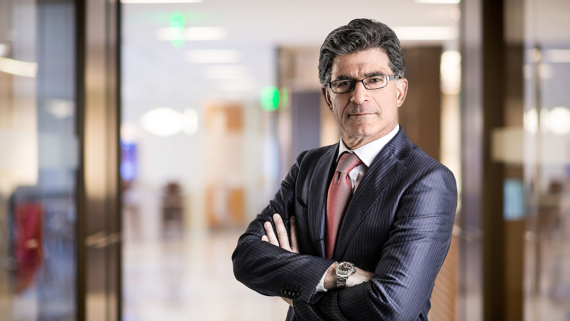 Male boss stands with arms crossed in an office setting