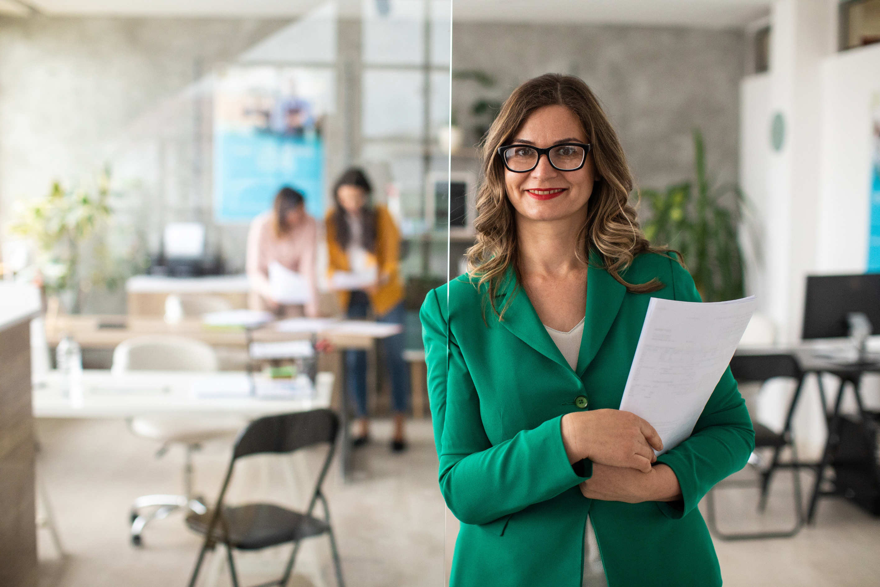 business woman in a green suit stands in an office workplace